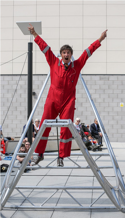 Man outside in red overalls on a metal frame